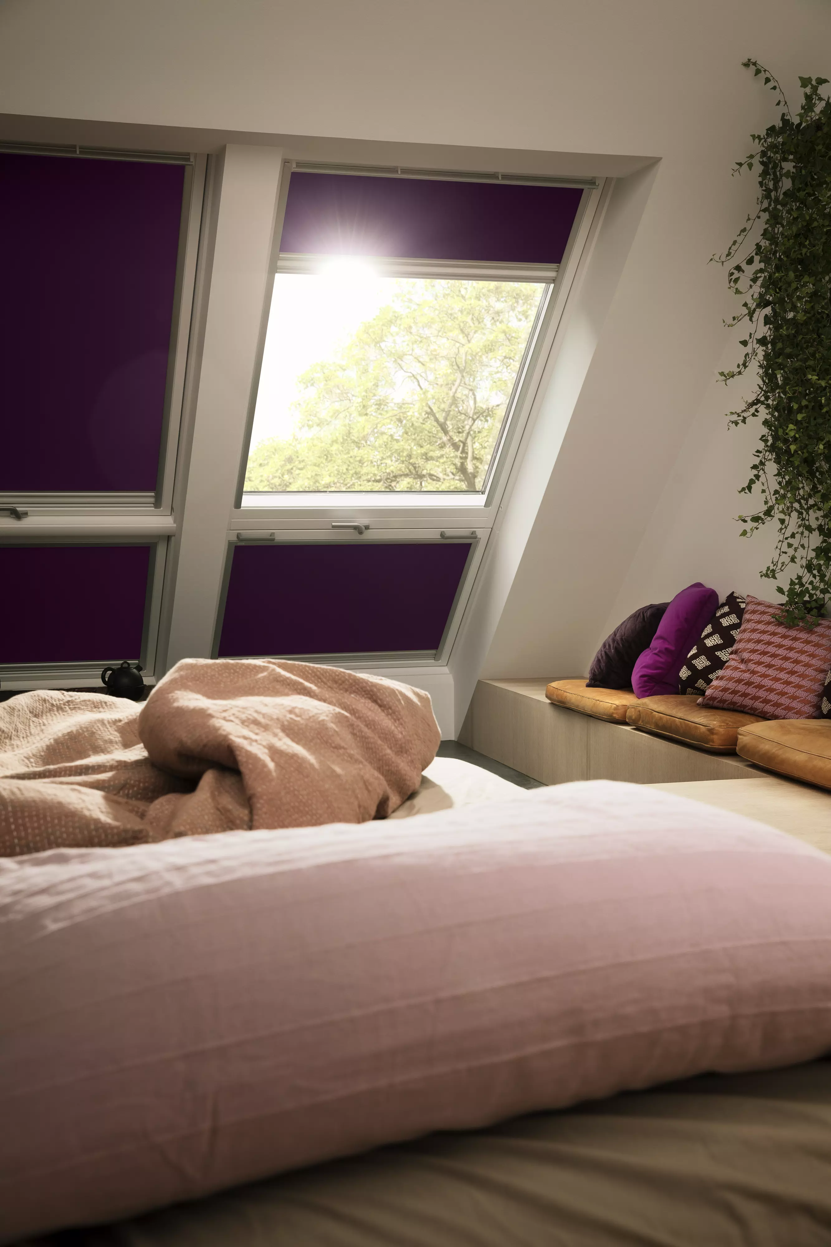Interior room with a steep sloping roof and VELUX blinds on four windows, showing blackout coverage with one blind open